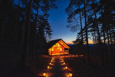 Lit Cabin in Forest at Night