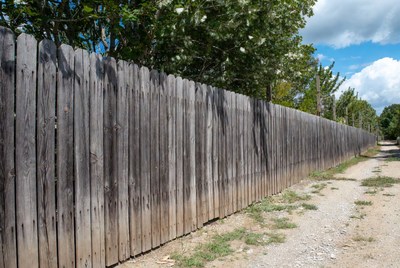 Wooden privacy fence along dirt path