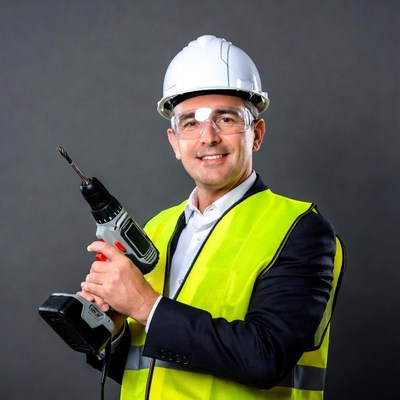 Man holding drill in hard hat vest