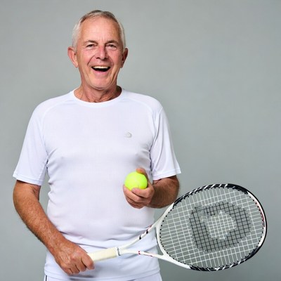 Senior man holding tennis racket and ball