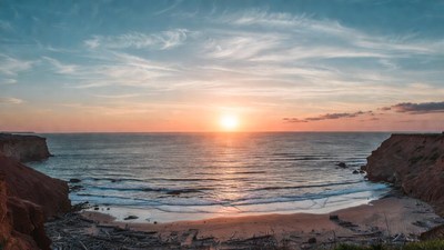 Sunset over ocean beach with cliffs