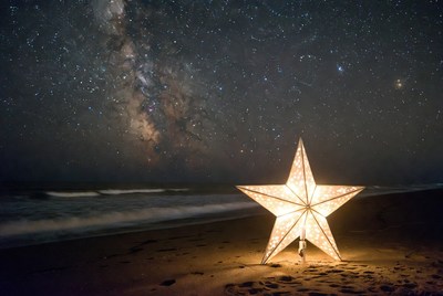 Girl beside glowing star lantern on beach