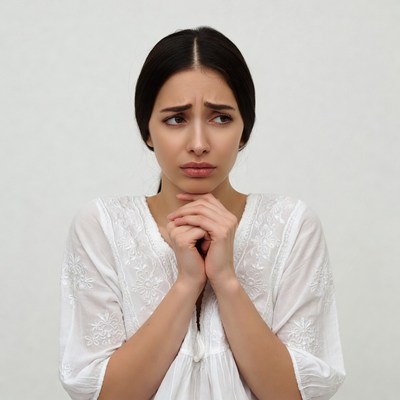Woman with hands clasped worried expression