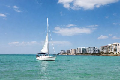 White sailboat in turquoise water near condos