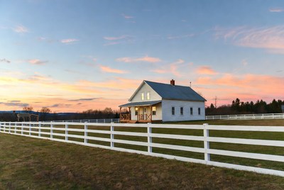 White farmhouse at sunset with white fence