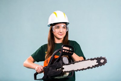 Woman holding chainsaw with hardhat