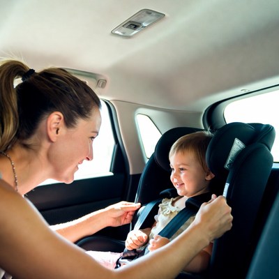 Mother buckling baby into car seat