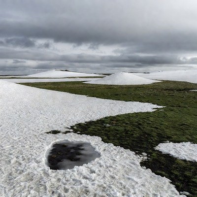 Snow-Covered Hills in Grassy Tundra