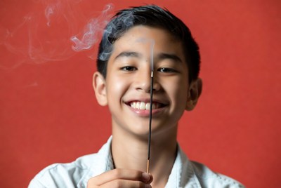 Asian boy holding lit incense stick