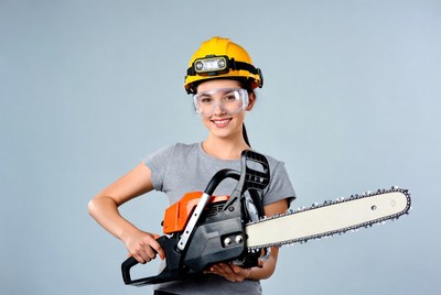 Woman holding chainsaw with helmet