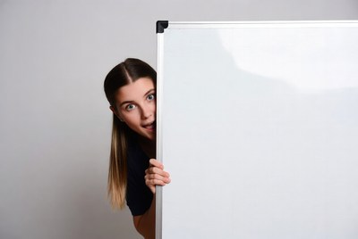 Woman peeking from behind whiteboard