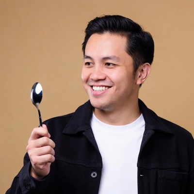 Asian man holding spoon smiling