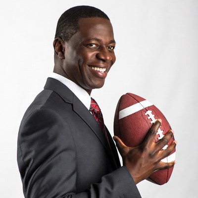 African-American man holding football in suit