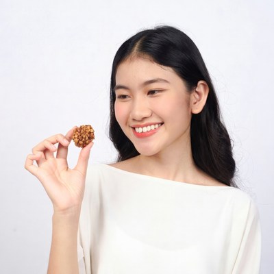 Asian woman holding small brown cookie