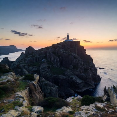 Lighthouse on rocky cliff at sunset