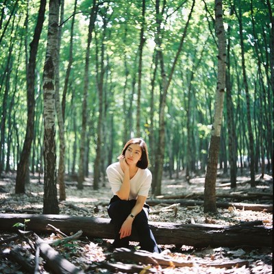 Asian woman sitting on log in birch forest