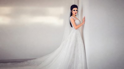 Bride in white gown leaning on wall
