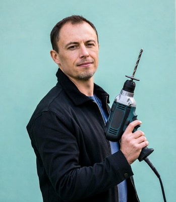 Man holding drill on teal background