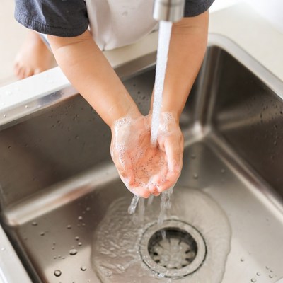 Child washing hands under faucet