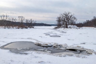 Frozen River with Ice Pools and Bare Trees