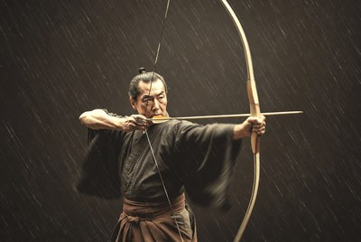 Samurai drawing bow in rain