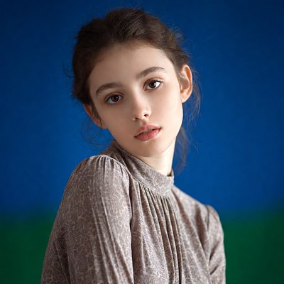 Young girl in taupe dress on blue background
