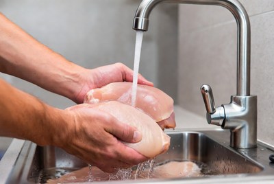 Man washing raw chicken breasts