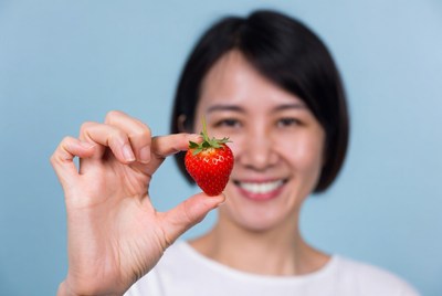 Asian woman holding fresh strawberry