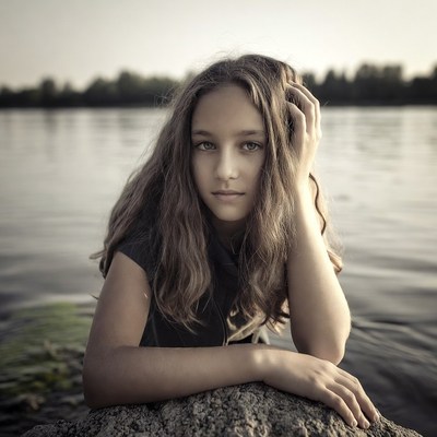 Girl resting chin on arms in river