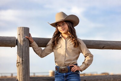 Girl in cowboy hat leaning on fence