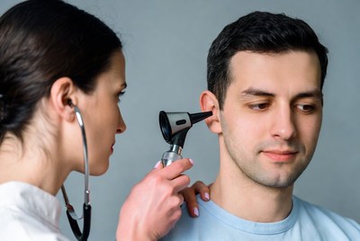 Doctor examining man's ear with otoscope