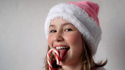 Girl licking pink candy cane