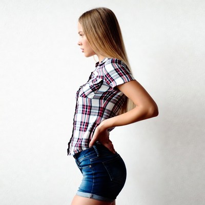 Woman in plaid shirt and denim shorts side profile