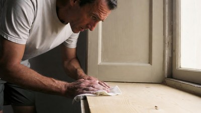 Man wiping wooden windowsill