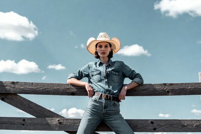 Woman in cowboy hat leaning on fence