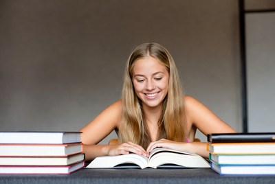 Smiling blonde girl reading book at desk