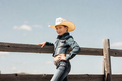 Girl in cowboy hat leaning on fence