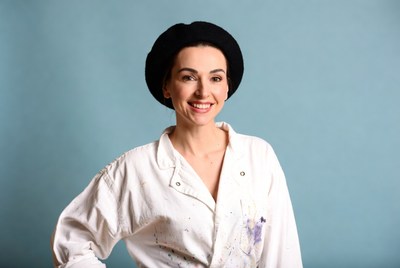 Smiling woman in beret and paint-splattered shirt