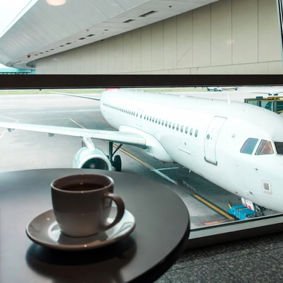 Coffee cup by airport window with airplane