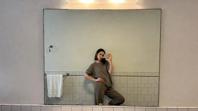 Woman taking selfie in bathroom mirror