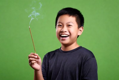 Asian boy holding lit incense stick