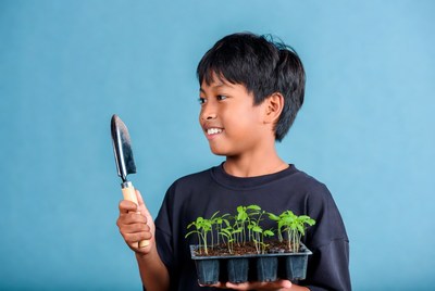 Asian boy holding seedlings and trowel
