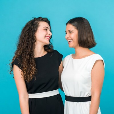 Two women smiling together blue background