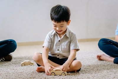 Asian boy playing with wooden toy cars