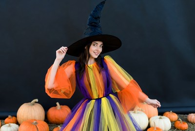 Woman in colorful witch costume with pumpkins