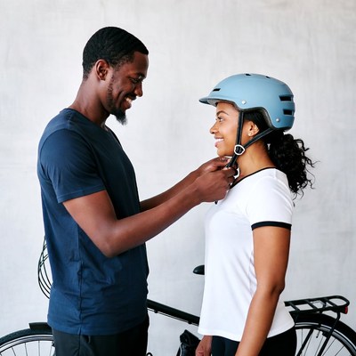 Man adjusting helmet on smiling woman