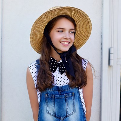 Girl in straw hat and polka dot overalls