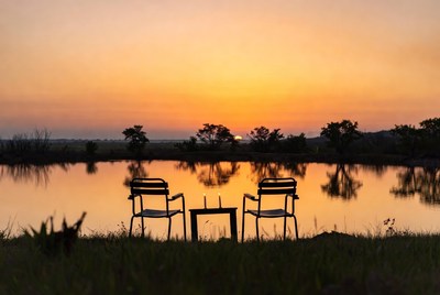 Two chairs and table at sunset lake