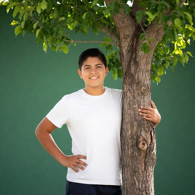 Latino boy smiling by tree