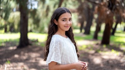 Smiling girl in white dress in forest